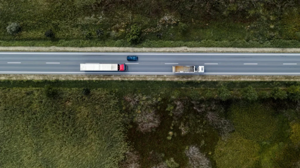 Blue car overtaking two trucks on a highway in the United States of America.