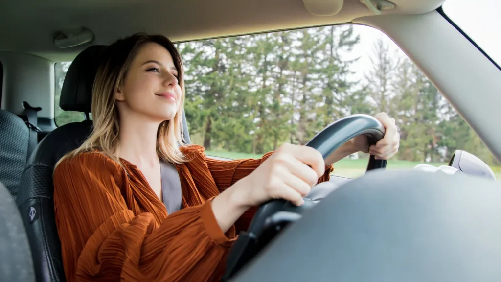 woman sitting on a driver place and hold a steering wheel